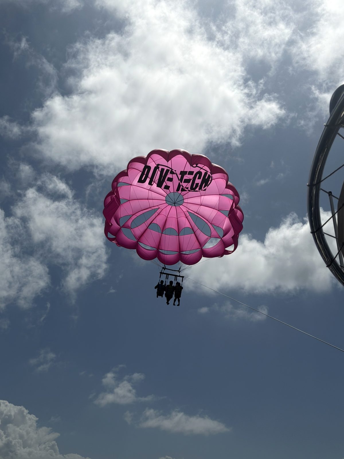A pink DiveTech parasail high against a blue sky