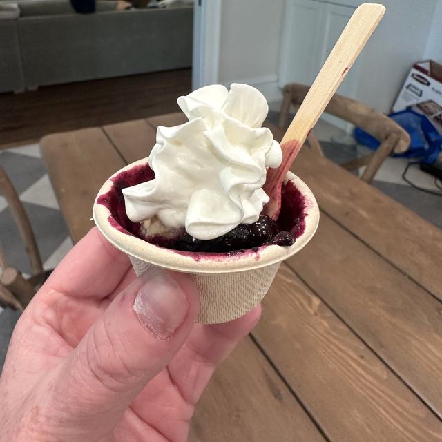 A mini cup of blueberry grunt topped with whipped cream