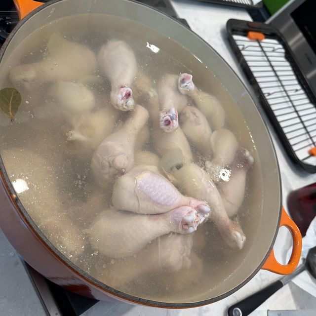 Drumsticks simmering in a big orange Dutch oven