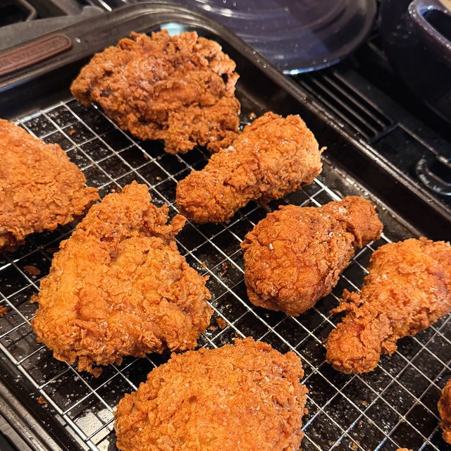 Three golden fried chicken drumsticks on a cooling rack