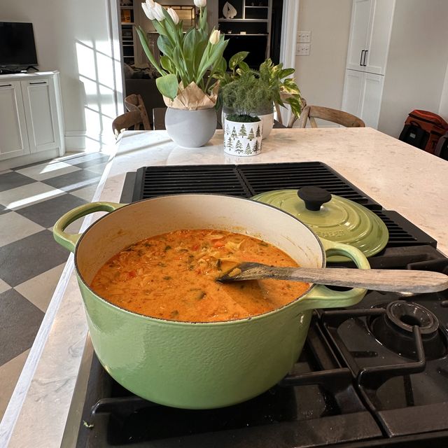 A sage green Le Creuset Dutch oven of soup on the stove in Heather's kitchen