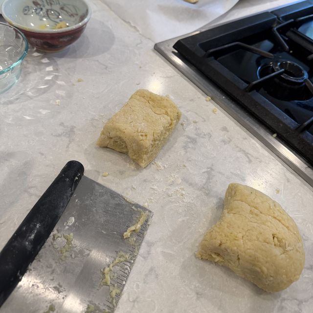 A stainless steel bench scraper next to a cut ball of gnocchi dough