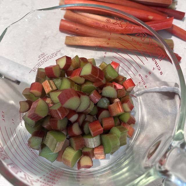 Thicker rhubarb stalks trimmed on the counter beside a measuring cup of chopped rhubarb